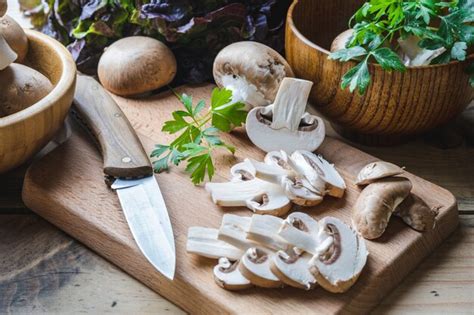 Ganso troceado y champiñones frescos en una tabla de cortar, listos para cocinar