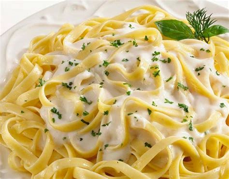 Plato terminado de tallarines con salsa blanca cremosa, espolvoreado con queso rallado.