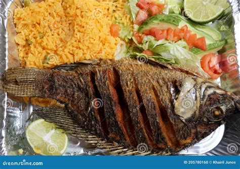 Plato de pescado frito con ensalada de lechuga, arroz y limón