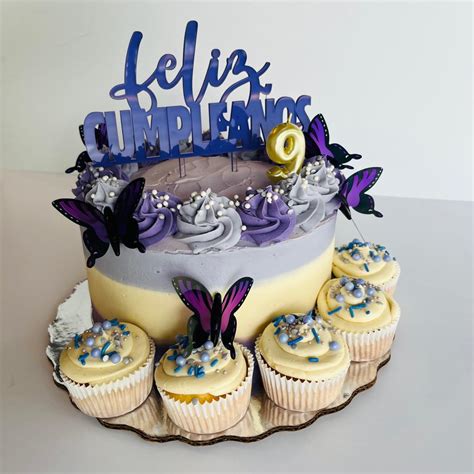 Mesa con una variedad de cupcakes, galletas y un pastel de cumpleaños