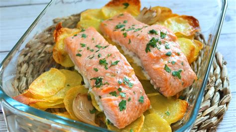 Fotografía gastronómica de un plato de salmón al horno servido sobre una cama de papas doradas con hierbas frescas.