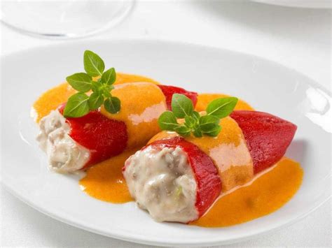 Fotografía de pimientos del piquillo rellenos, servidos con su salsa.