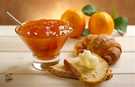 Imagen de primer plano de mermelada de naranja y zanahoria en un frasco de vidrio sobre una tostada