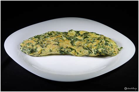 Foto temática de un omelette de acelga recién preparado bañado en salsa de jitomate, decorado con hierbas frescas