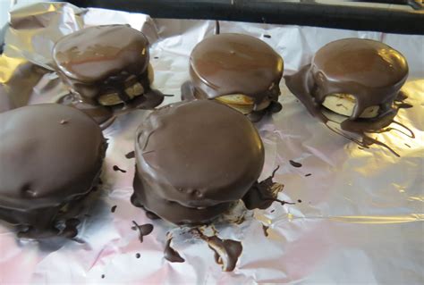 Alfajores recién bañados en chocolate, secándose sobre papel manteca.