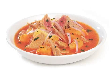 Plato de encebollado de atún siendo decorado con atún, cebolla y cilantro