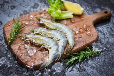 Camarones frescos, verduras variadas y especias sobre una tabla de cortar