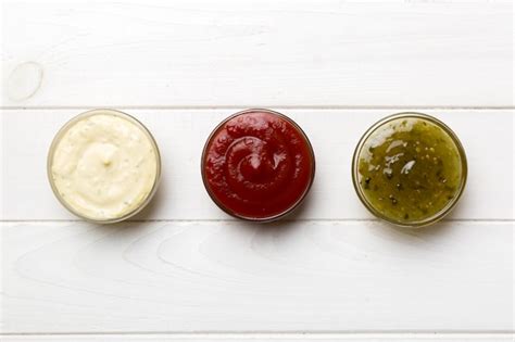Varias salsas barbecue de diferentes colores y texturas en pequeños cuencos, mostrando variedad de sabores