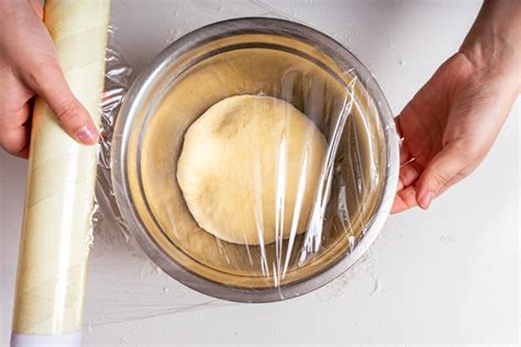 Bola de masa de pasta reposando envuelta en film transparente