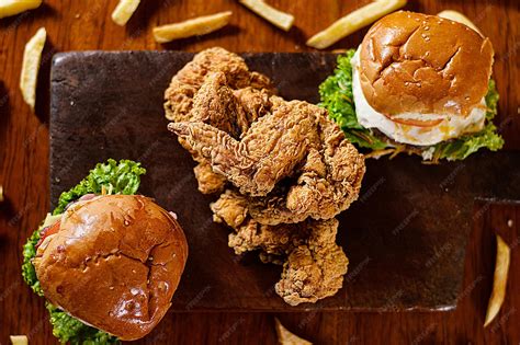 mesa con hamburguesa de pollo frito y acompañamientos variados