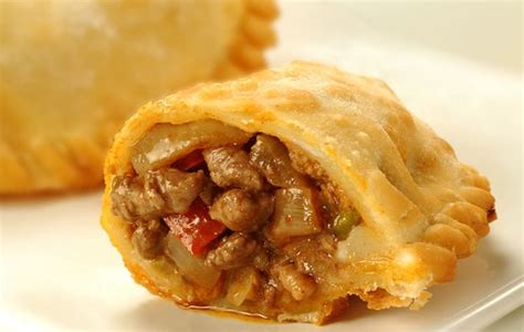 Primer plano de una empanada de queso mantecoso frita, cortada para mostrar el interior