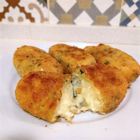 Croquetas de papa rellenas cortadas por la mitad mostrando el queso derretido