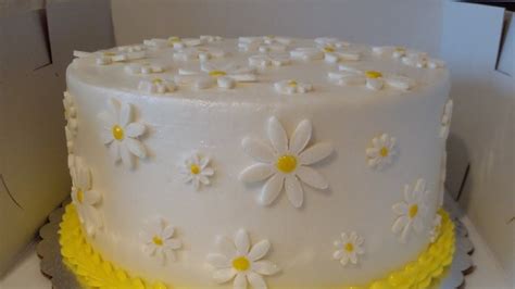Imagen de un bizcocho decorado con fondant blanco en forma de margaritas.