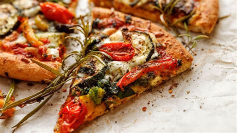 Pizza casera con base de espinacas, decorada con queso feta y tomates cherry