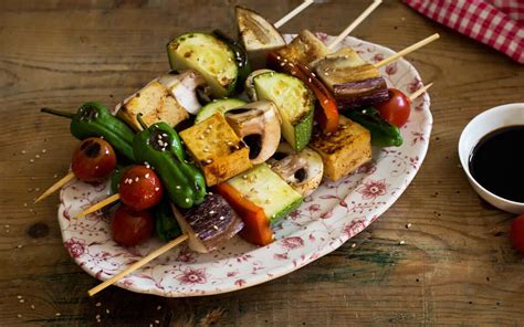 Brochetas de verduras y tofu con un toque tailandés, servidas con salsa.