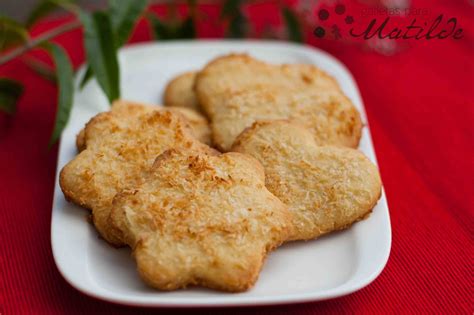 Fotografía profesional de galletas de mantequilla y coco doradas dispuestas sobre una rejilla con coco rallado de fondo
