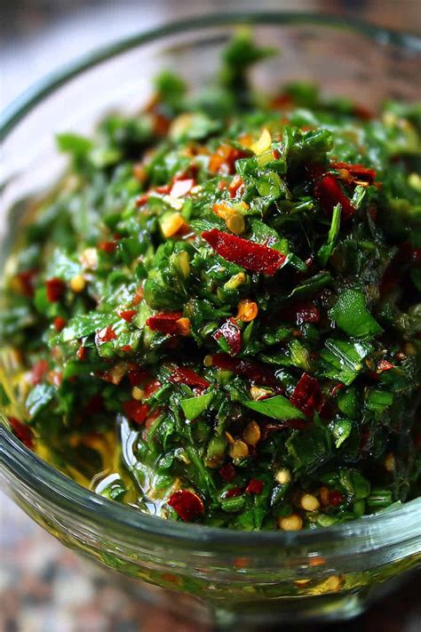 Chimichurri casero en un recipiente con hierbas frescas