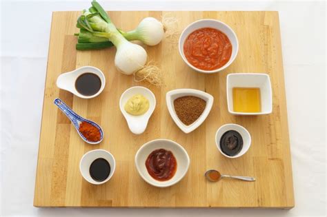 Tabla con ingredientes frescos y especias organizados para la preparación de la salsa barbacoa.