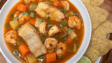 Foto de un plato humeante de caldo de pescado con cilantro y limón