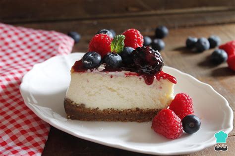 Plato con porción de cheesecake decorado con frutos rojos y salsa