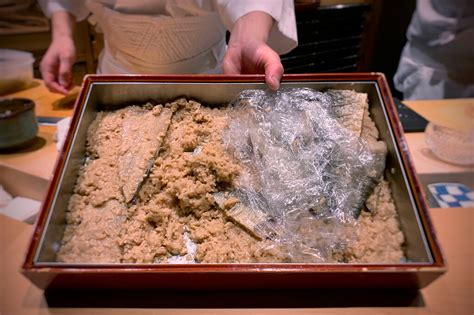 Ilustración histórica que muestra un antiguo método de preparación de sushi, posiblemente narezushi o oshizushi.