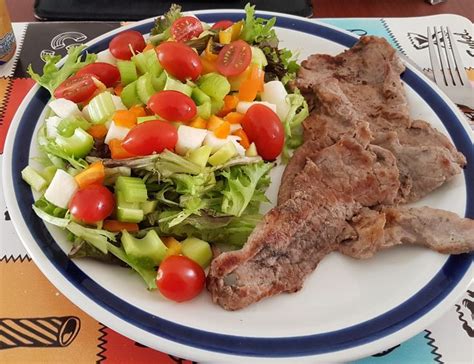 Plato de carne roja con una guarnición de verduras al vapor y una ensalada fresca, sin carbohidratos.