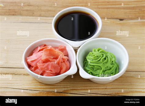 Imagen de varios cuencos pequeños con salsa de soja, wasabi y jengibre encurtido, junto a una copa de sake y una copa de vino blanco.