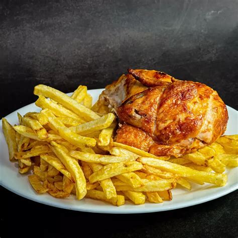 Fotografía de un jugoso pollo a las brasas con papas fritas y ensalada