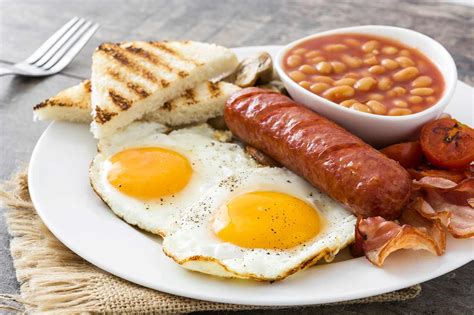 Plato de desayuno inglés completo donde se distinguen las judías en salsa de tomate junto a huevos, salchichas y bacon.