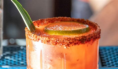 Detalle de un vaso siendo escarchado con sal y chile piquín.