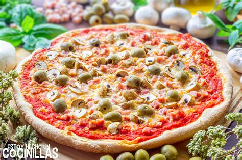 Pizza casera con jamón, queso, tomate, champiñones y aceitunas antes de hornear