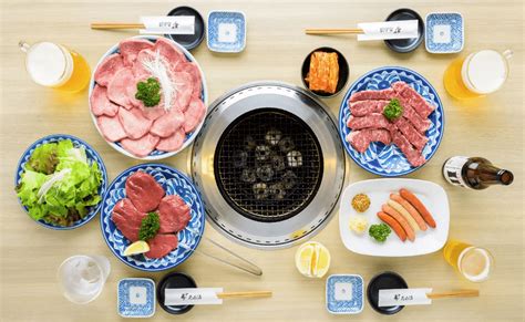 Parrilla de yakiniku en el centro de una mesa con varios cortes de carne