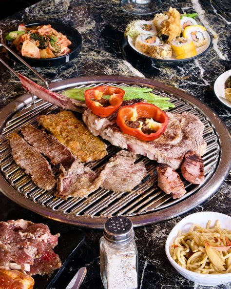 Mesa de Korean BBQ con una parrilla central y múltiples platillos de acompañamiento
