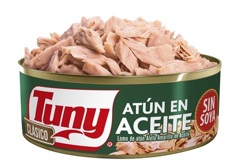 Imagen de una lata de atún abierta con el pescado en su interior, acompañada de algunos vegetales frescos para ensalada.