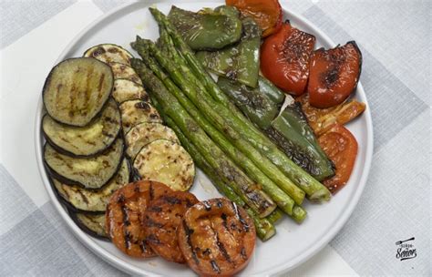 Foto de una parrillada con carne, verduras y un bol de salsa barbacoa.