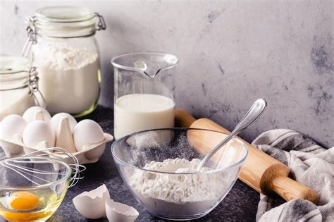 Una cesta de huevos frescos junto a ingredientes de panadería como harina, azúcar y levadura.