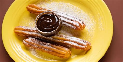 Churros recién hechos espolvoreados con azúcar y acompañados de chocolate caliente