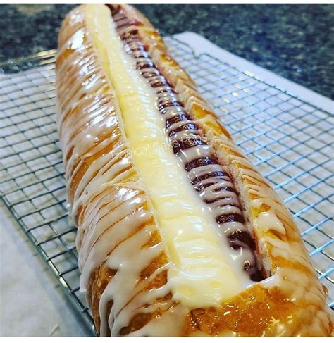 Fotografía profesional de pan de guayaba y queso recién horneado con corteza dorada y relleno visible.