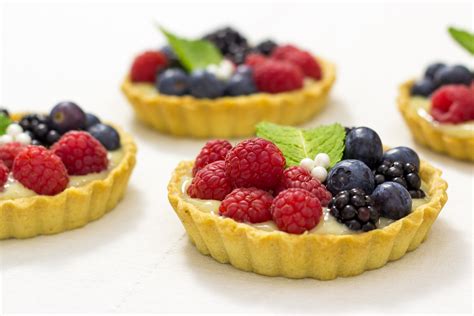 Infografía con los componentes clave de las tartaletas de frutas: masa quebrada, relleno cremoso (sin crema pastelera tradicional), frutas frescas y un glaseado opcional.