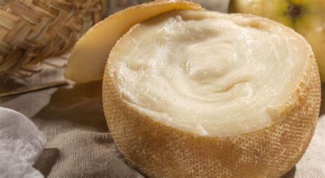 primer plano de un trozo de queso Torta del Casar con una porción de dulce de membrillo