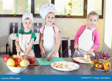 Niños preparando ensalada de frutas en una cocina