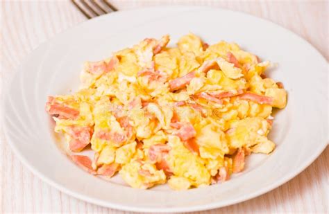Plato de huevos revueltos con jamón y queso, acompañado de espinacas
