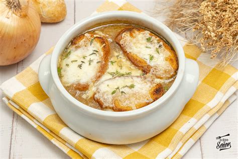 Un tazón humeante de sopa de cebolla dorada, con pan integral y queso ligero gratinado encima