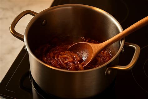 Primer plano de cebollas caramelizándose lentamente en una olla de fondo grueso