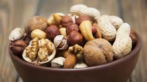 Frutos secos frescos (maní, almendras, avellanas) en un cuenco, con un tarro de mantequilla de frutos secos