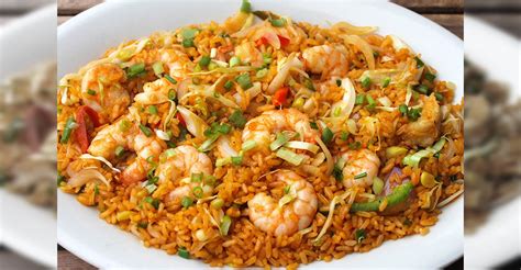 Plato de arroz con camarones servido en un recipiente decorado con cilantro fresco y gajos de limón.
