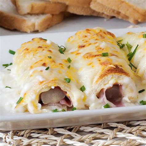 Crepes enrollados en un molde para horno, cubiertos con bechamel y queso
