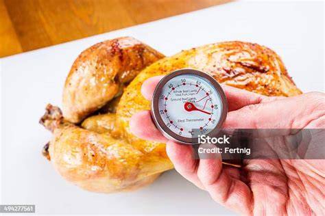 termómetro de cocina insertado en un pollo asado