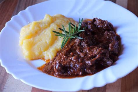 Plato de estofado con polenta, adornado con perejil fresco y ralladura de limón