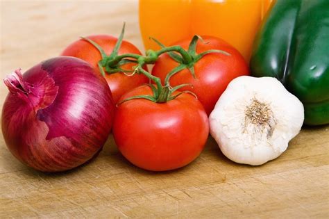 Esquema de los ingredientes frescos como tomate, cebolla, ajo y zanahoria dispuestos para ser procesados en licuadora.